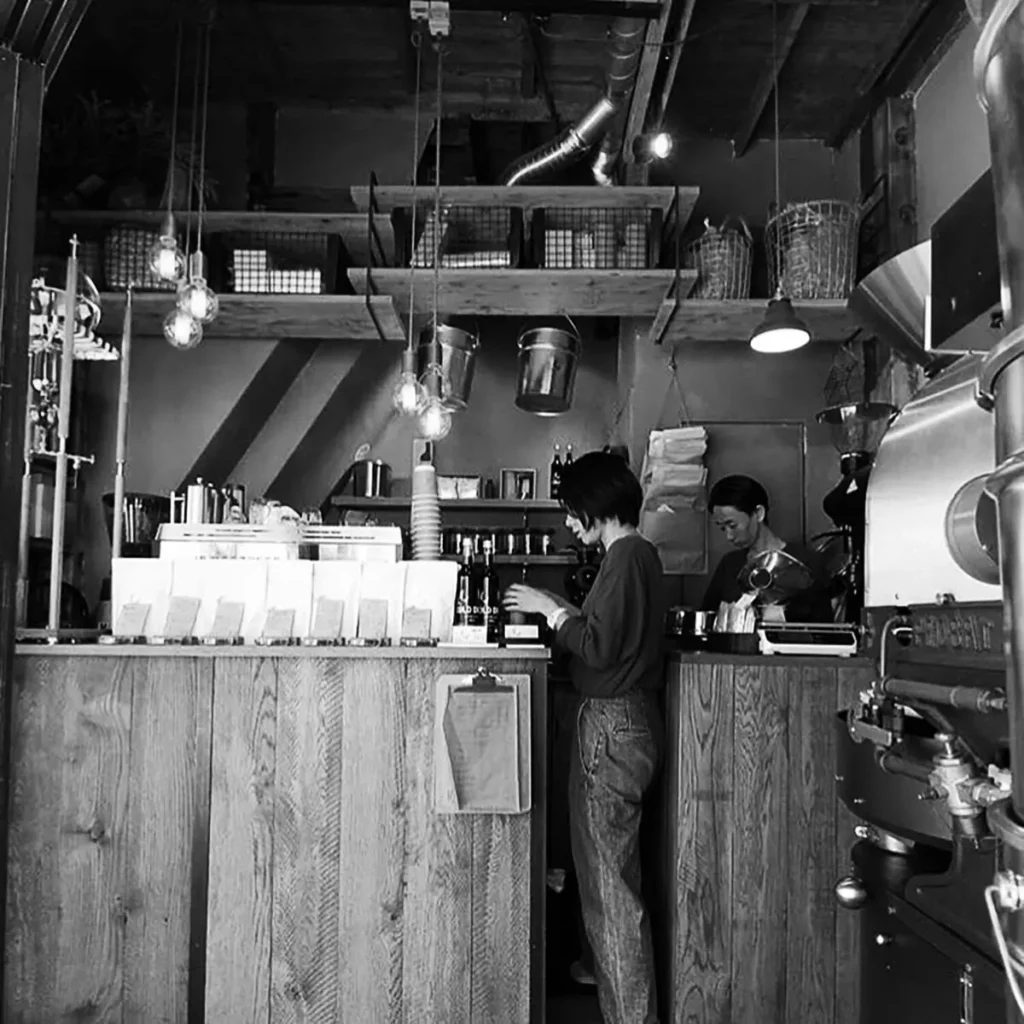 Masa Nakashima, founder of Mel Coffee Roasters in Japan, standing in front of coffee roasters, specializing in third wave and specialty coffee roasting.